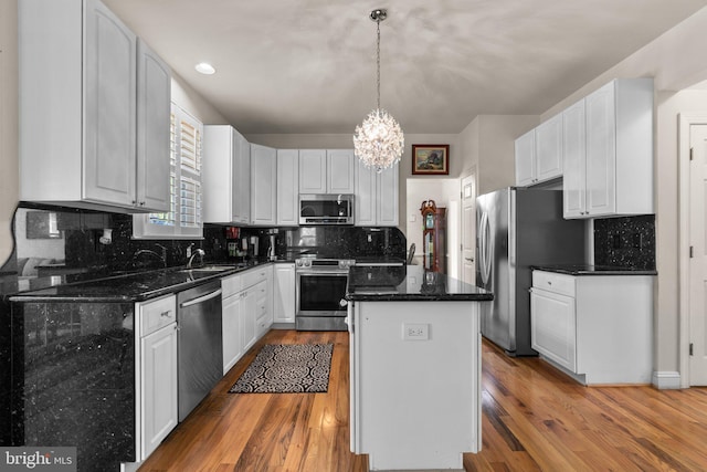 kitchen with a kitchen island, stainless steel appliances, a chandelier, and wood finished floors