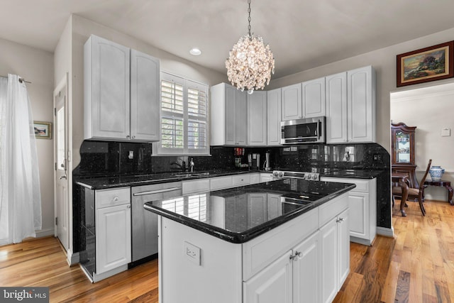 kitchen with an inviting chandelier, tasteful backsplash, stainless steel appliances, and white cabinetry