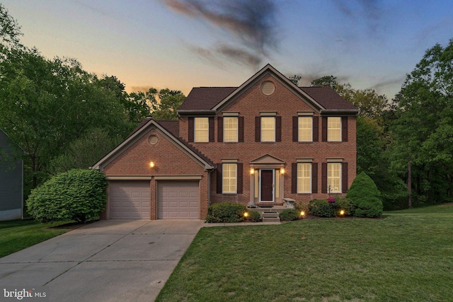 colonial home featuring an attached garage, concrete driveway, brick siding, and a front yard