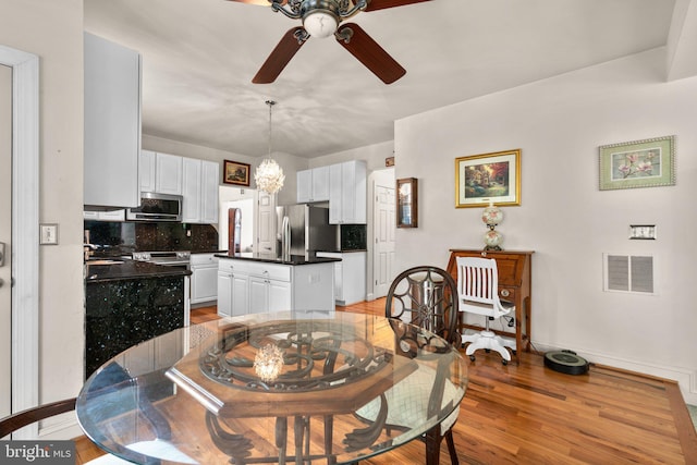 dining space featuring visible vents, light wood-style flooring, baseboards, and ceiling fan