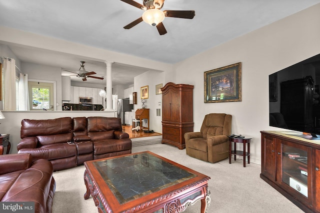 living room with a ceiling fan, light colored carpet, and decorative columns