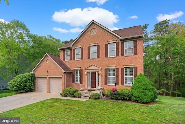 colonial home with concrete driveway, brick siding, a front yard, and a garage