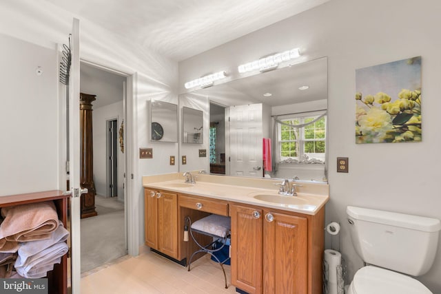 full bathroom with double vanity, toilet, a sink, and tile patterned floors