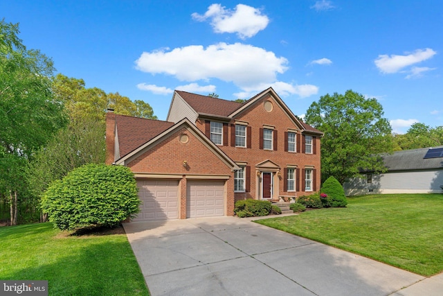 colonial-style house with an attached garage, a chimney, driveway, and brick siding