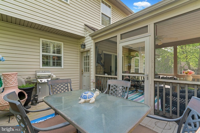 wooden deck featuring a sunroom, a grill, and outdoor dining space