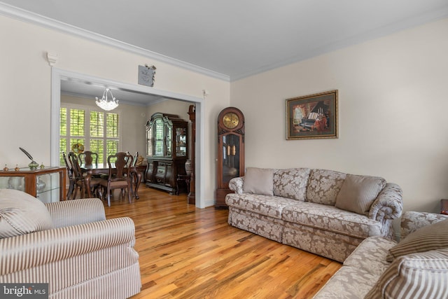 living room with a chandelier, ornamental molding, and light wood-style flooring