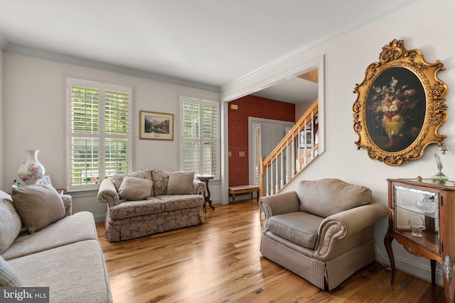 living area with ornamental molding, stairs, and wood finished floors