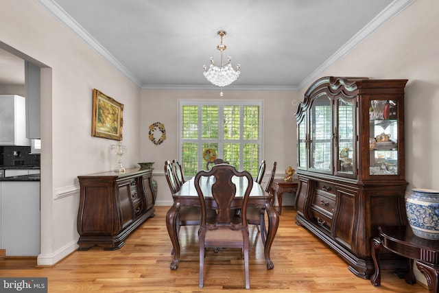dining space featuring crown molding, light wood finished floors, baseboards, and a chandelier
