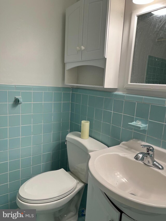 half bath featuring a sink, tile walls, and toilet