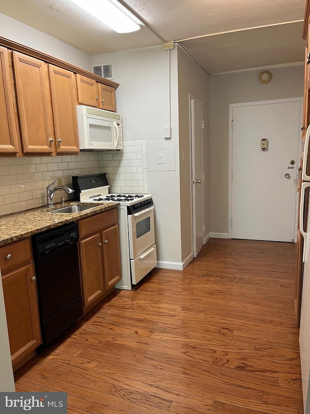 kitchen featuring light stone countertops, light wood-style floors, white appliances, backsplash, and visible vents