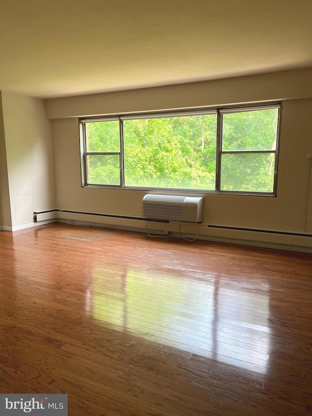 unfurnished room featuring an AC wall unit and hardwood / wood-style flooring