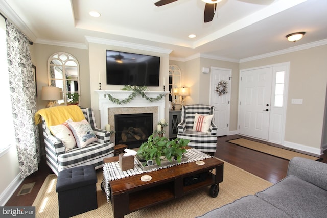 living room featuring baseboards, a ceiling fan, wood finished floors, and a tray ceiling