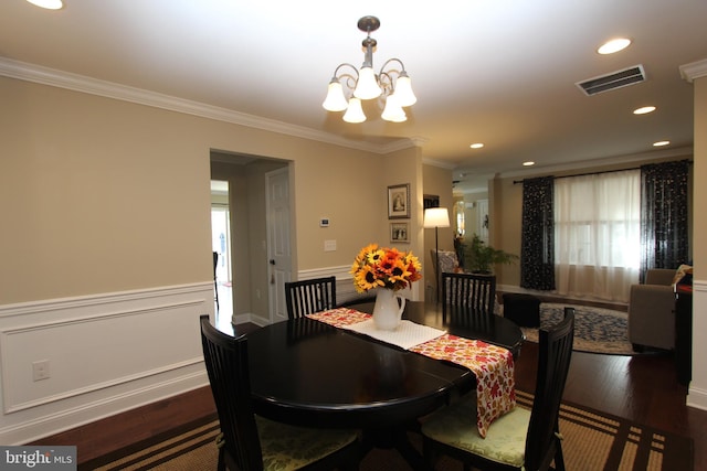 dining area featuring visible vents, crown molding, dark wood-style flooring, wainscoting, and a notable chandelier