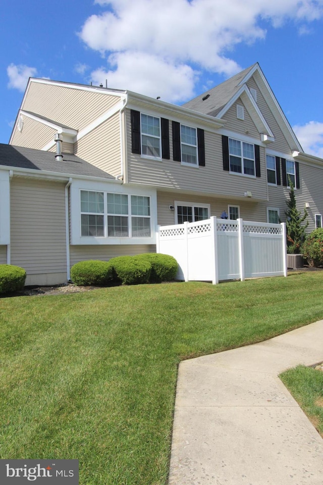 view of front of property featuring fence, cooling unit, and a front yard