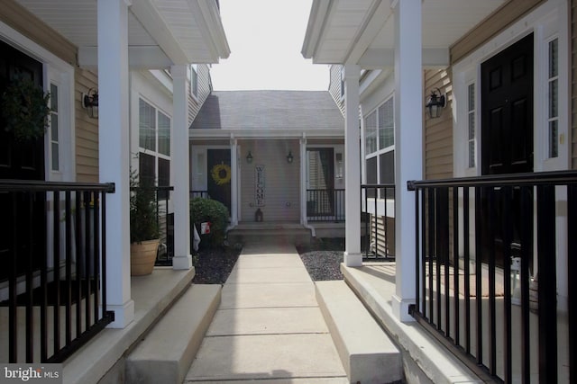property entrance featuring covered porch and a shingled roof