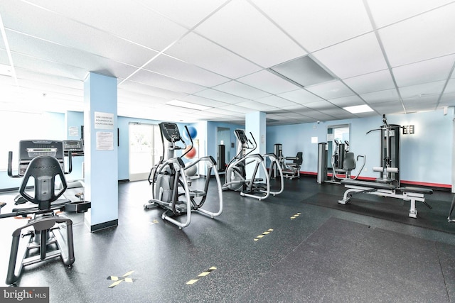 exercise room with baseboards and a paneled ceiling