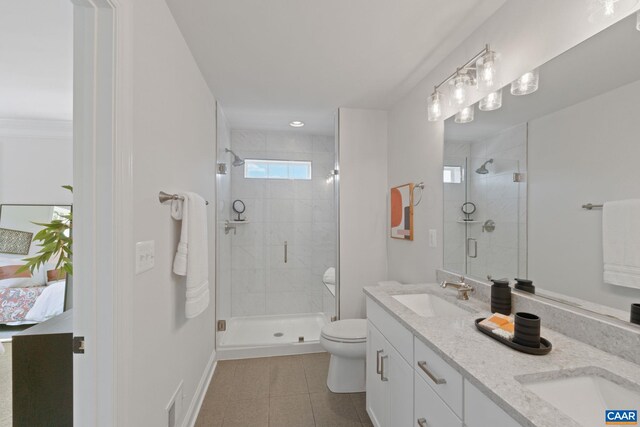 ensuite bathroom with tile patterned flooring, a sink, a stall shower, and toilet