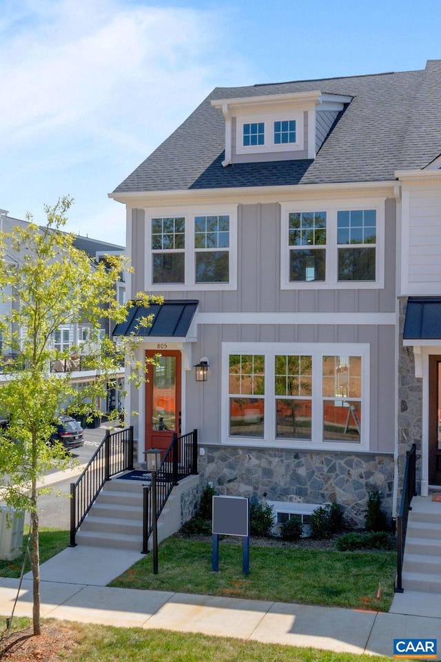 view of front of house with board and batten siding, roof with shingles, and stone siding