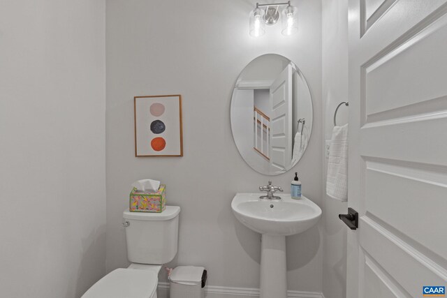 half bath featuring baseboards, a sink, and toilet