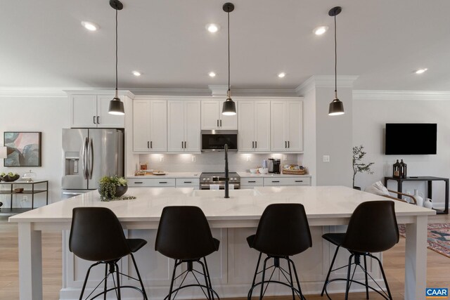 kitchen with white cabinets, crown molding, stainless steel appliances, tasteful backsplash, and a spacious island