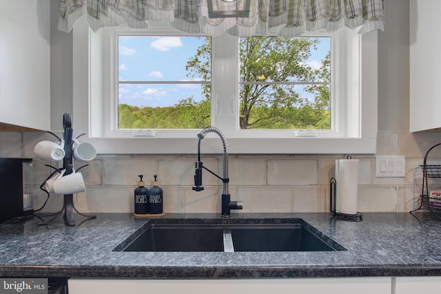 kitchen with a sink, decorative backsplash, and white cabinets