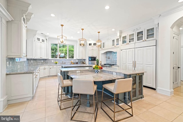 696 Miller Ave, Great Falls, VA 22066 - kitchen featuring a large island with sink, light tile patterned flooring, black microwave, arched walkways, and decorative backsplash