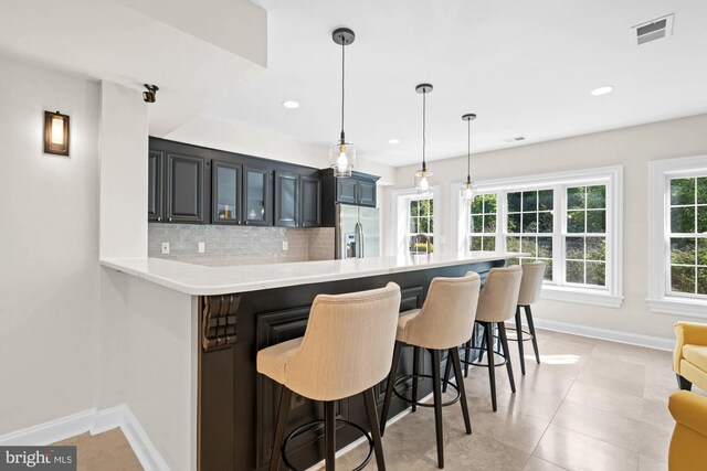 696 Miller Ave, Great Falls, VA 22066 - kitchen with baseboards, a breakfast bar, stainless steel refrigerator with ice dispenser, backsplash, and light countertops