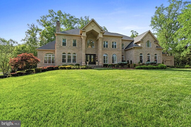 696 Miller Ave, Great Falls, VA 22066 - colonial house featuring a chimney, stone siding, roof with shingles, and a front lawn