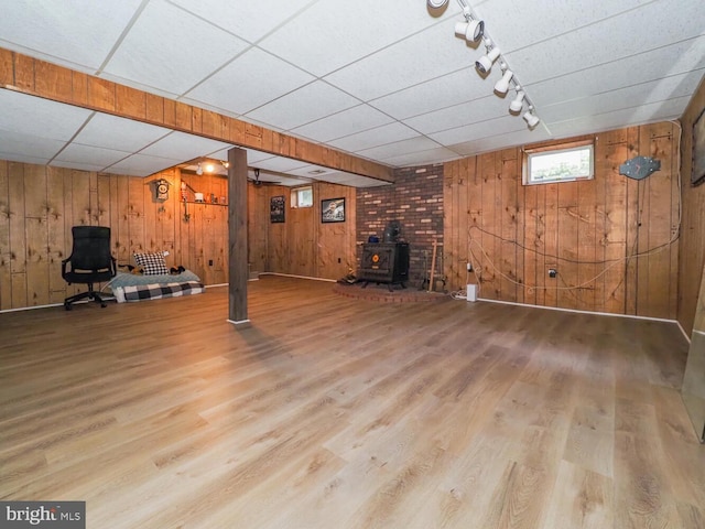 1235 Lorene Dr, Pasadena, MD 21122 - below grade area with wooden walls, a wood stove, wood finished floors, track lighting, and a drop ceiling