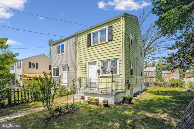 rear view of property with a lawn and fence