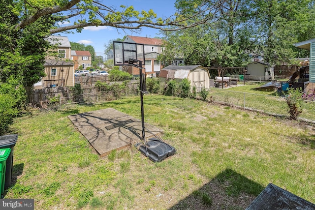 view of yard with an outdoor structure, a fenced backyard, a storage shed, and a residential view