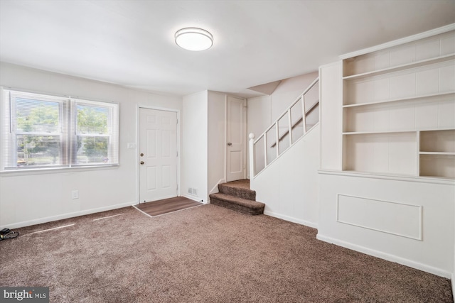 entryway with stairway, baseboards, and carpet