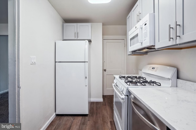 kitchen with white appliances, light stone countertops, dark wood finished floors, and baseboards