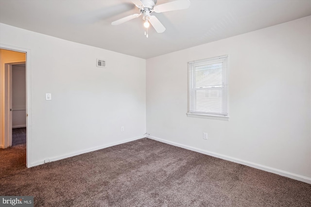 empty room featuring a ceiling fan, baseboards, visible vents, and dark carpet