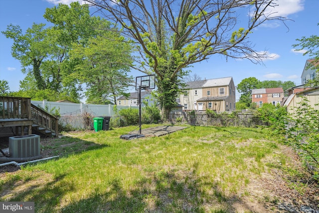 view of yard featuring a fenced backyard, central AC, and a residential view