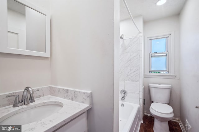 bathroom featuring vanity, wood finished floors, bathing tub / shower combination, and toilet