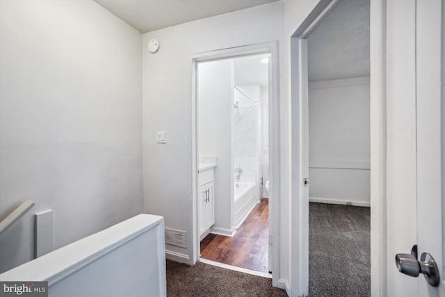 hall featuring baseboards and dark carpet