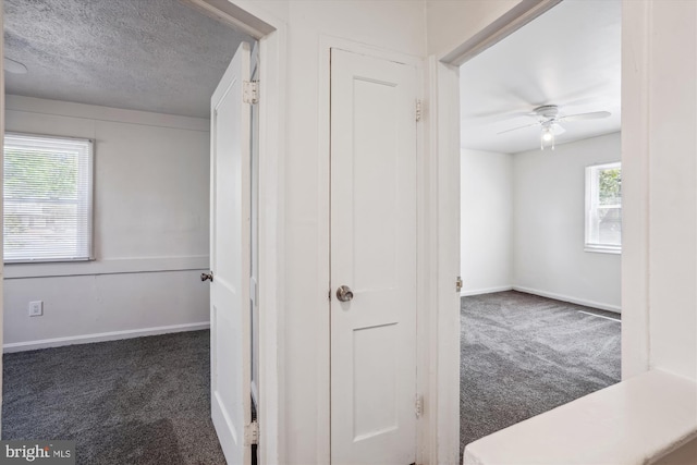 hall featuring carpet flooring, a textured ceiling, and baseboards