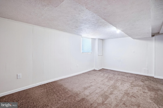 basement featuring baseboards, carpet, and a textured ceiling