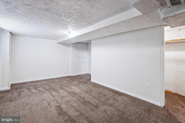 finished below grade area featuring baseboards, a textured ceiling, and carpet