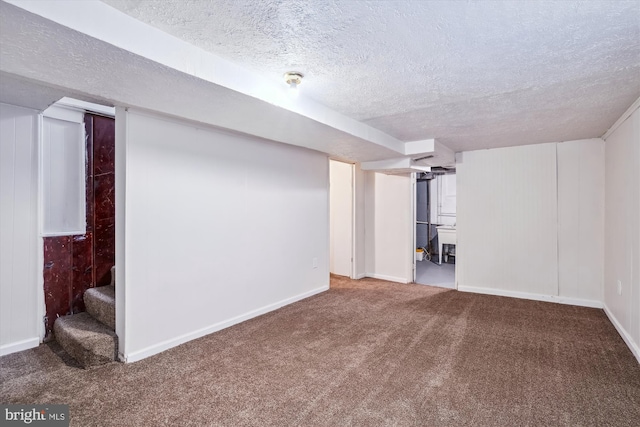finished below grade area featuring stairway, carpet floors, baseboards, and a textured ceiling
