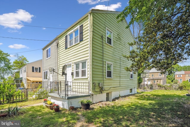 back of property featuring fence and a lawn