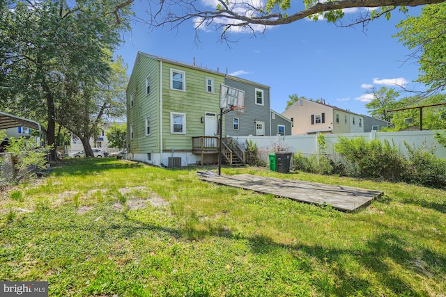 back of house with fence, central AC unit, and a lawn