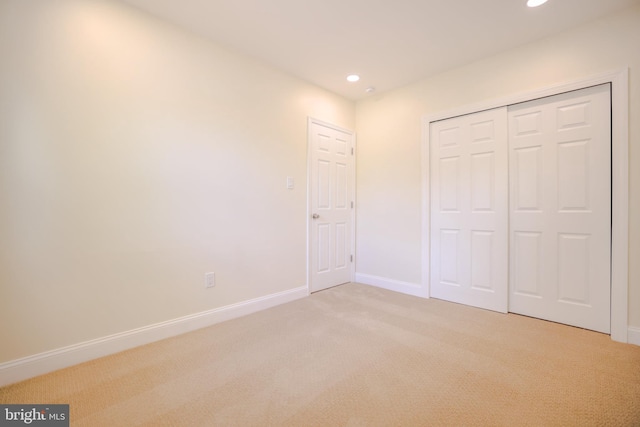 unfurnished bedroom featuring recessed lighting, baseboards, light colored carpet, and a closet