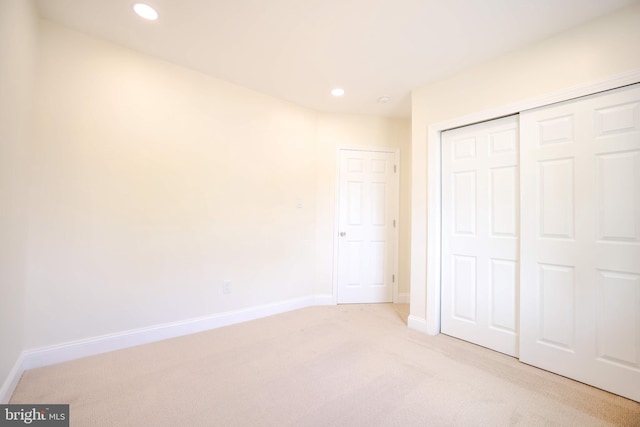unfurnished bedroom with recessed lighting, baseboards, light carpet, and a closet