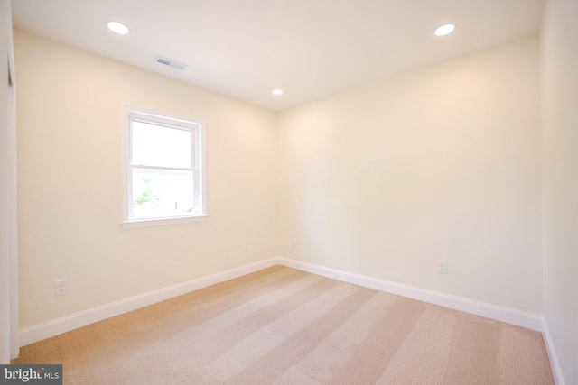 empty room with baseboards, light carpet, recessed lighting, and visible vents