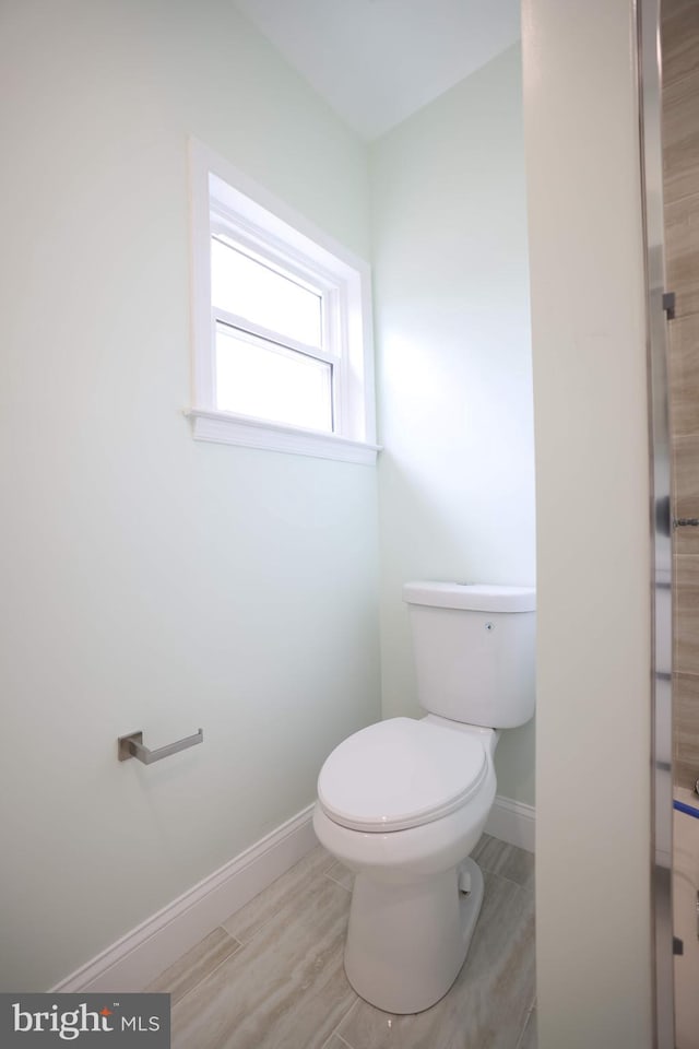 bathroom with baseboards, wood finished floors, and toilet