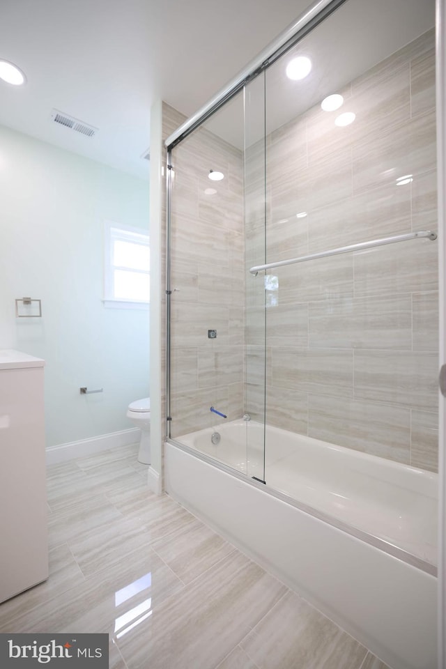 full bath featuring shower / bath combination with glass door, vanity, toilet, baseboards, and visible vents