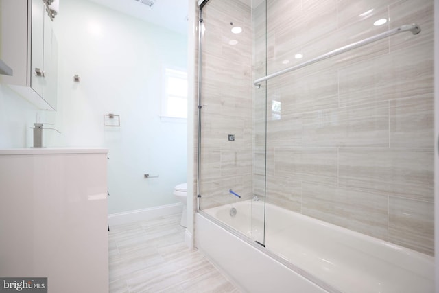 bathroom with visible vents, vanity, shower / bath combination with glass door, toilet, and baseboards
