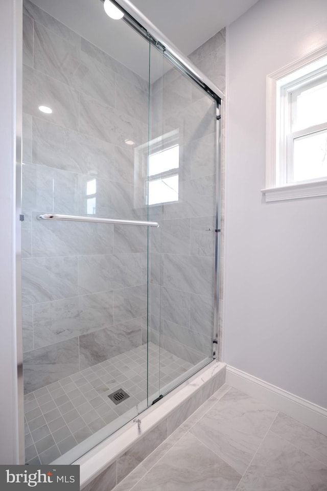 full bathroom with baseboards, plenty of natural light, and a stall shower